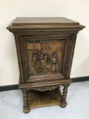 A carved oak cabinet on stand