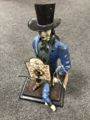 A painted metal figural clock depicting a gentleman in top hat