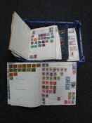 A basket containing seven assorted mid 20th century stamp albums with stamps