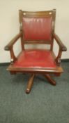 A late Victorian oak swivel office chair with red studded leather,