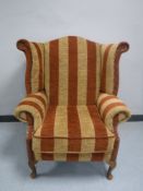 A 20th century wing back armchair re-upholstered in striped fabric