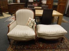 A Victorian style upholstered armchair with matching oversized footstool in striped fabric.