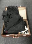 A large brown leather suitcase containing a collection of vintage clothing