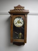An early 20th century oak cased wall clock with enamelled dial,
