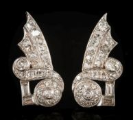 A pair of early 20th century diamond earrings: of scroll ribbon design with graduated old,