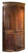 An early 19th Century mahogany and inlaid bow-fronted standing corner cupboard:,