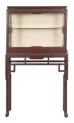A Chinese hardwood rectangular display cabinet on a stand:, having glazed panel front,