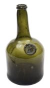 An 18th century sealed glass wine bottle: of squat cylinder form with shallow kick up,