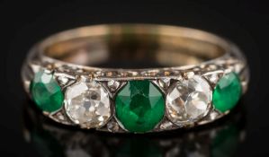 An emerald and diamond five-stone ring: with graduated oval emeralds between old brilliant-cut