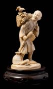 A Japanese carved ivory okimono of a woodcutter: the figure in traditional robes holding an axe in
