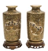 A pair of Japanese Satsuma vases: each decorated with groups of ladies and flowering shrubs within