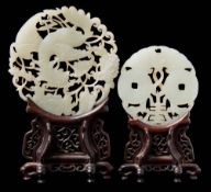 Two Chinese carved and pierced celadon jade discs: the larger in the form of a phoenix amongst