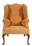 A carved walnut wing frame armchair in the early 18th Century taste:, fully upholstered,