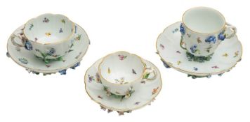 A group of three Meissen floral encrusted cabinet cups and saucers: with entwined stalk handles,