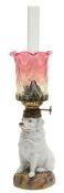 A Continental porcelain oil lamp in the form of a dog: seated on mound base,