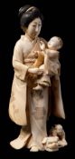 A Japanese carved ivory okimono of a bijin: carrying a young boy,