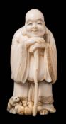 A Japanese ivory okimono of Hotei, signed Gyokugetsu: the smiling god leaning on his staff,
