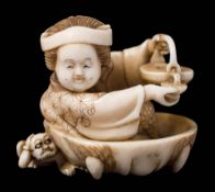 A Japanese carved ivory okimono of Okame, signed Seizan: seated in a large mask of an oni,