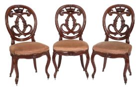 A set of four Victorian carved mahogany dining chairs:, the oval moulded backs with crown,