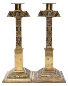 A pair of Middle Eastern brass candlesticks: with cylindrical nozzles and cruciform capitals on