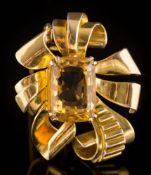 A cushion-shaped citrine single-stone brooch: of stylised ribbon scroll design,