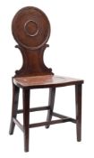 A George III mahogany hall chair:, the circular moulded panel back with C-scroll uprights,