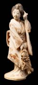 A Japanese carved ivory okimono of a bijin: wearing traditional Kimono adjusting her hair with her