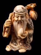 A Japanese carved ivory and stained netsuke depicting a Sennin: in traditional costume holding a