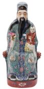 A Chinese famille rose figure of Shou Lao: the seated Immortal wearing elaborate blue and turquoise