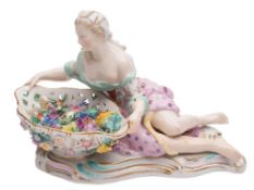 A Meissen figural sweetmeat dish: the shaped bowl applied with flowers and supported by a reclining