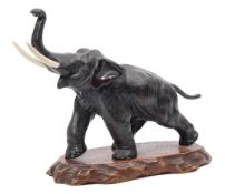 An early 20th century Japanese bronze model of a charging elephant: with faux ivory tusks and