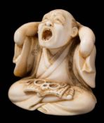 A Japanese carved ivory okimono of a yawning man, signed Yoshiyuki: seated cross-legged,