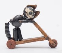 An early 20th century wooden Felix the Cat articulated figure riding a scooter,