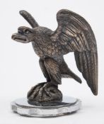 An eagle car mascot:, with raised wings seated on a rocky plinth,