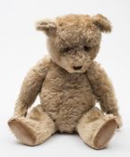 A blonde plush Teddy bear:, with glass eyes,