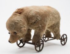 A late 19th/early 20th century blonde plush bear on wheels:, possibly Steiff,