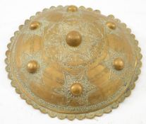 A 19th century Persian brass dhal:, with six raised bosses and floral pattern star decoration,