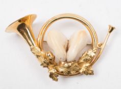 A hunting brooch in the form of a bugle:, comprising two stag teeth, the reverse stamped '750',