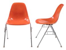 A pair of orange fibreglass and chrome plated chairs in the manner of Charles & Ray Eames,