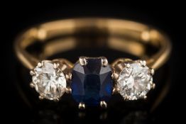 A sapphire and diamond three-stone ring: the central oval sapphire approximately 6mm long x 5.