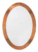 An oval copper framed wall mirror in the Arts & Crafts taste: the mirror plate enclose by a beaten
