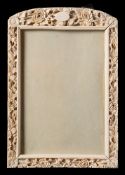 A Canton ivory rectangular frame: carved with a vacant cartouche and a continuous band of flowers