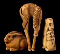Two Japanese ivory netsuke and a similar okimono: the netsuke in the form of a monkey clutching its