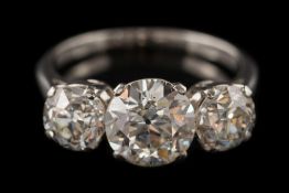 A diamond three-stone ring: the principal old European-cut diamond approximately 7.9mm diameter x 4.