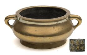 A Chinese cast bronze censer: of plain squat circular form with loop carrying handles to the sides,