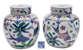 A pair of Chinese wucai jars and covers: painted overall with fish and crustacae swimming amongst