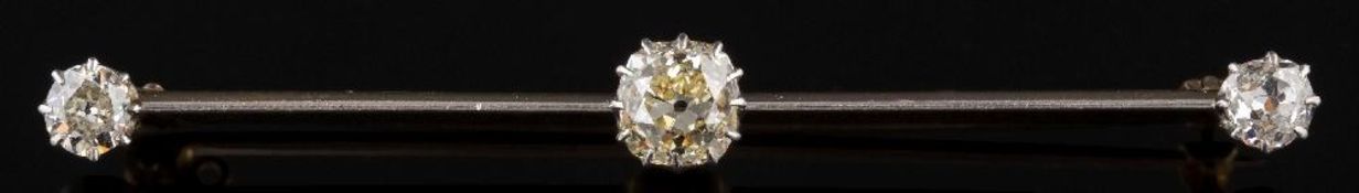 A diamond three-stone bar brooch: the central cushion-shaped old,