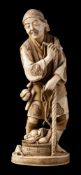 A Japanese carved ivory okimono of a peasant: standing holding a pipe in one hand and a staff in