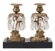 A pair of 19th century gilt brass candlesticks: in the form of dolphins, with urn-shaped nozzles,