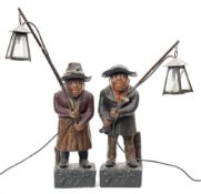 A pair of polychrome painted terracotta figures holding lamps: both wearing broad rim hats and